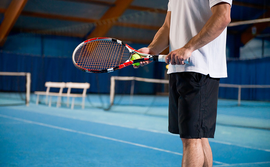 Close up shot of an indoor tennis player preparing for serving a ball.
