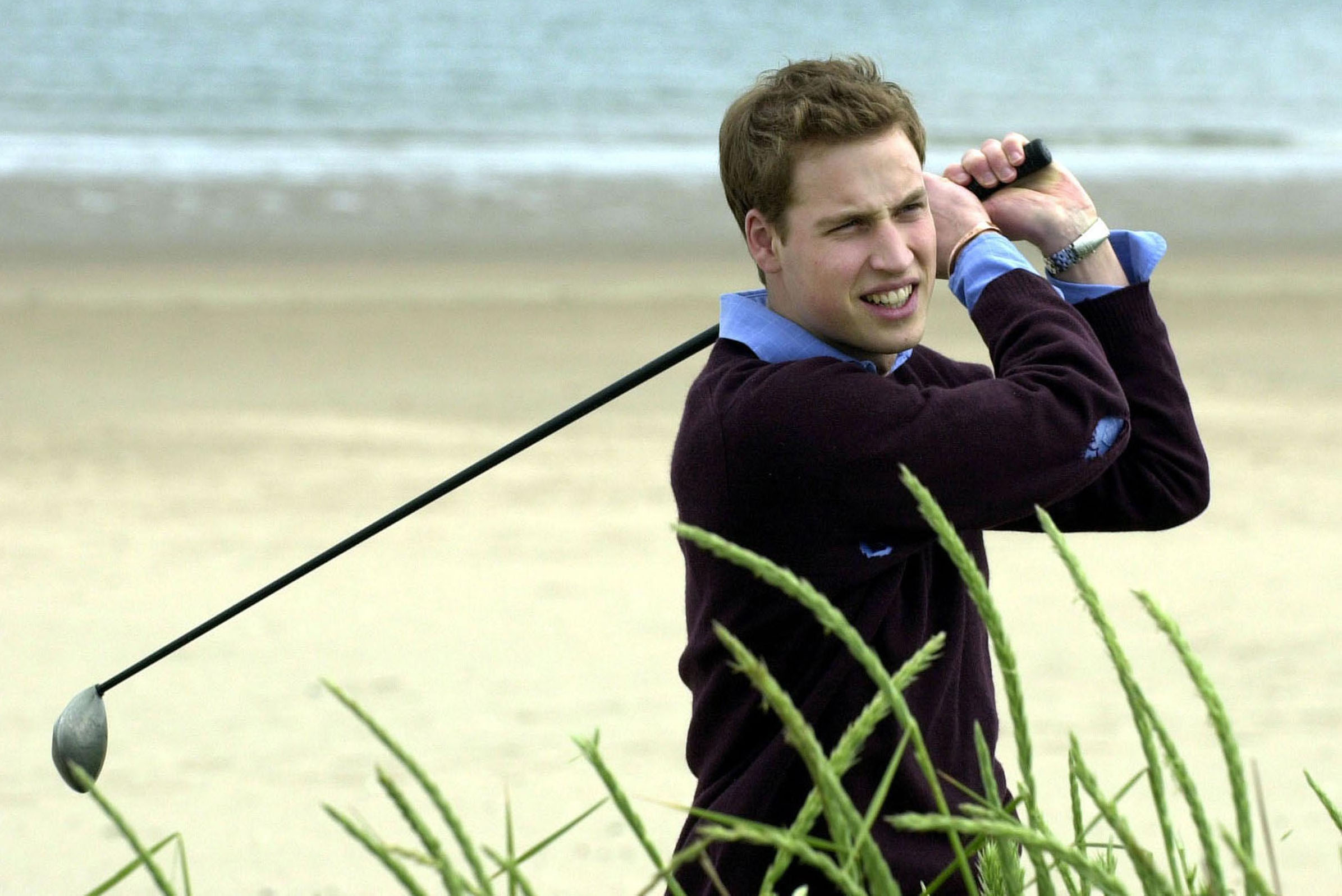 Prince William throws a practice his golf swing on the beach at St Andrews (PA)