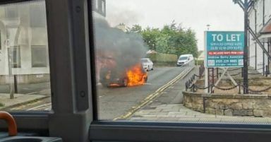 Car bursts into flames in middle of street blocking road