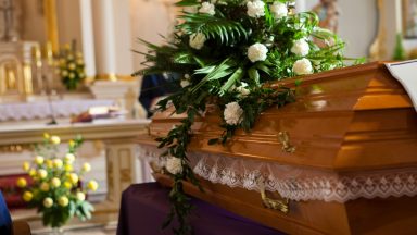 Stock image of flowers on a coffin at a funeral.
