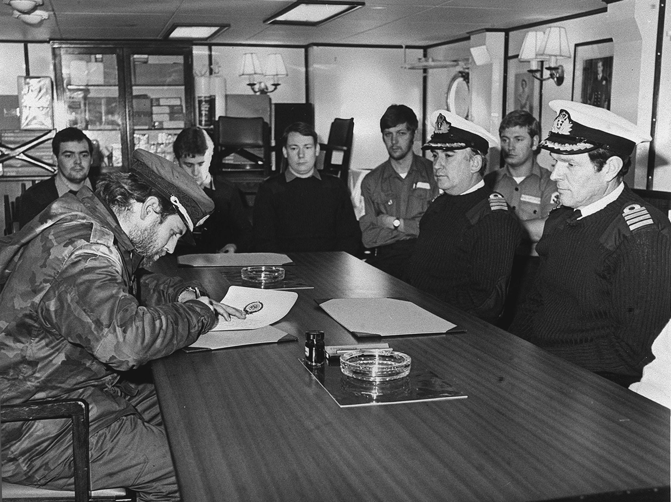 The Argentines from Leith, South Georgia, surrender to the British Forces on board HMS Plymouth. The Argentine representative, TNCB Alfredo Astiz signs the surrender document in front of the Captain of HMS Plymouth, Captain David Pentreath and Captain Nicholas Barker of HMS Endurande, in this picture issued by the MOD.