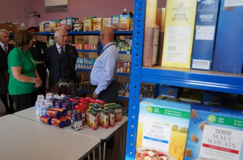 The Prince of Wales, known as the Duke of Rothesay when in Scotland, views food he has donated with Pat and Grant Ramsay.