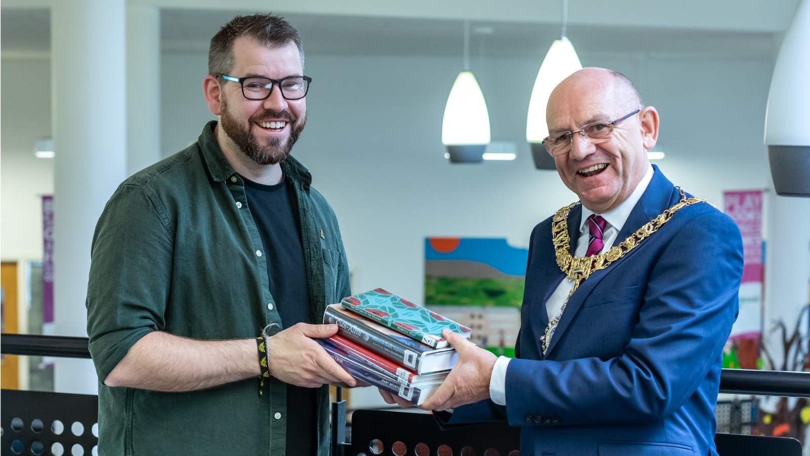 Robert Aldridge, Lord Provost of Edinburgh presents Joe Cain, Library Development Leader at Drumbrae Library Hub with a set of books from five of the city's overlooked women writers.