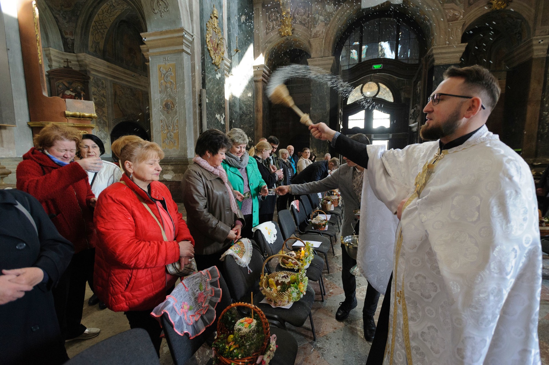 A Greek Catholic priest blesses Easter cakes at St Peter Church in Lviv, Ukraine (Mykola Tys/AP/PA) 