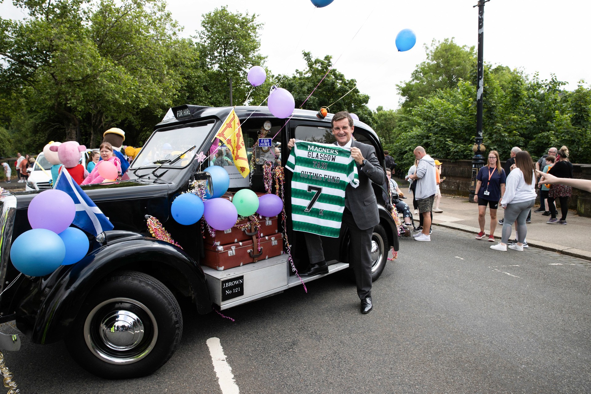 Celtic Legend Tosh McKinlay presents a £7,000 cheque to the Glasgow Taxi Outing Fund.