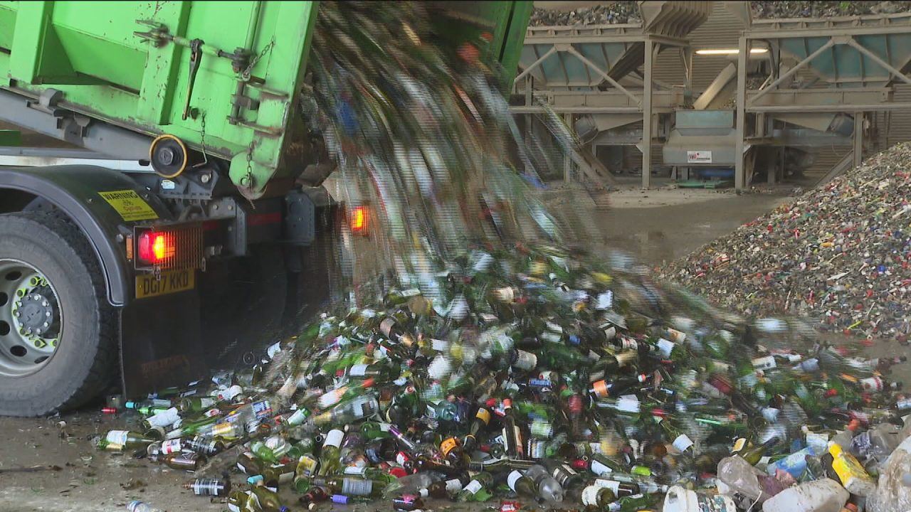 Glass bottles are seen being dumped out of a truck in a recycling centre