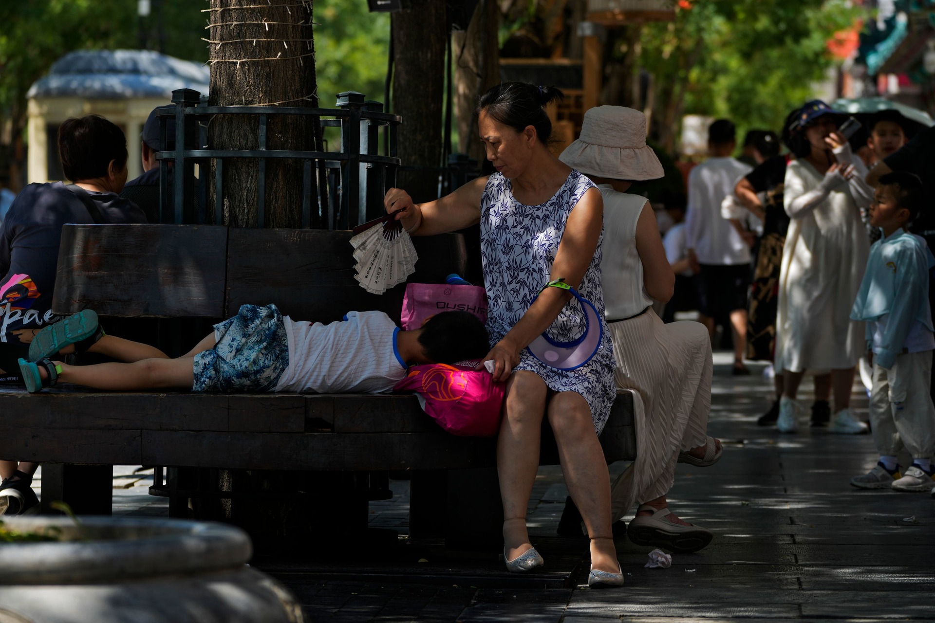 A woman uses a fan to cool a child in Beijing.