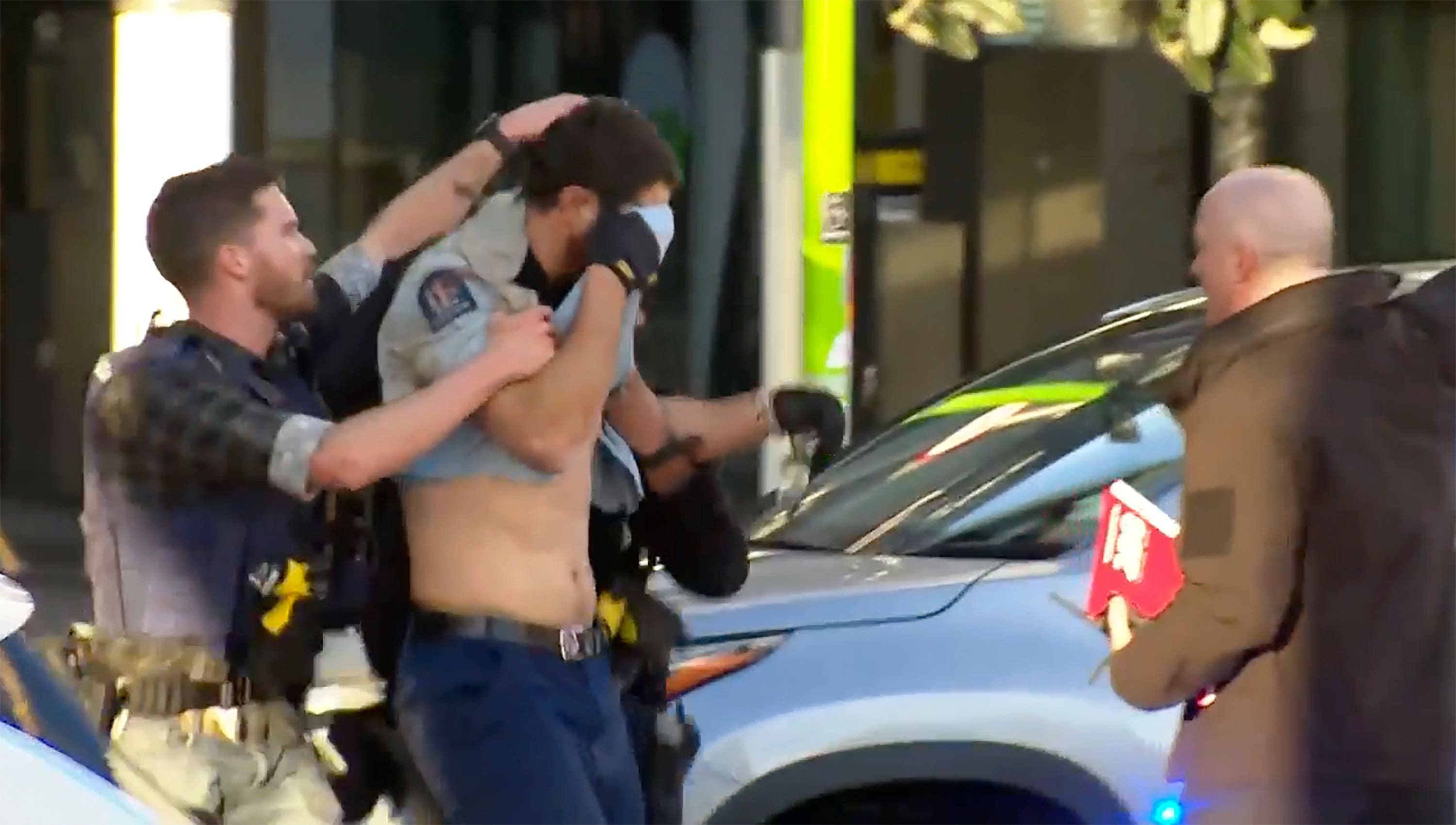 In this image from a video, an injured police officer, second left, is led away to be placed in an ambulance.