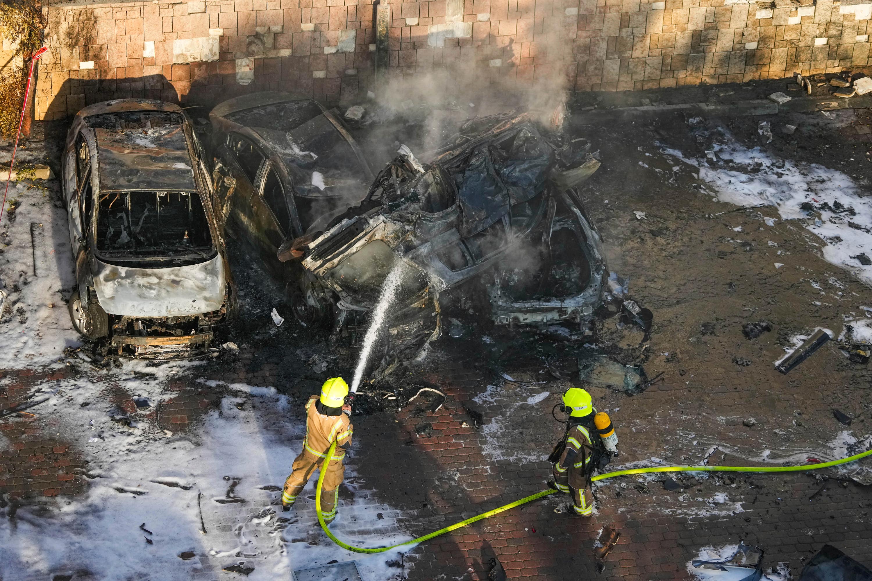 Israeli firefighters extinguish a blaze after a rocket fired from the Gaza Strip hit a car park in Ashkelon, southern Israel.