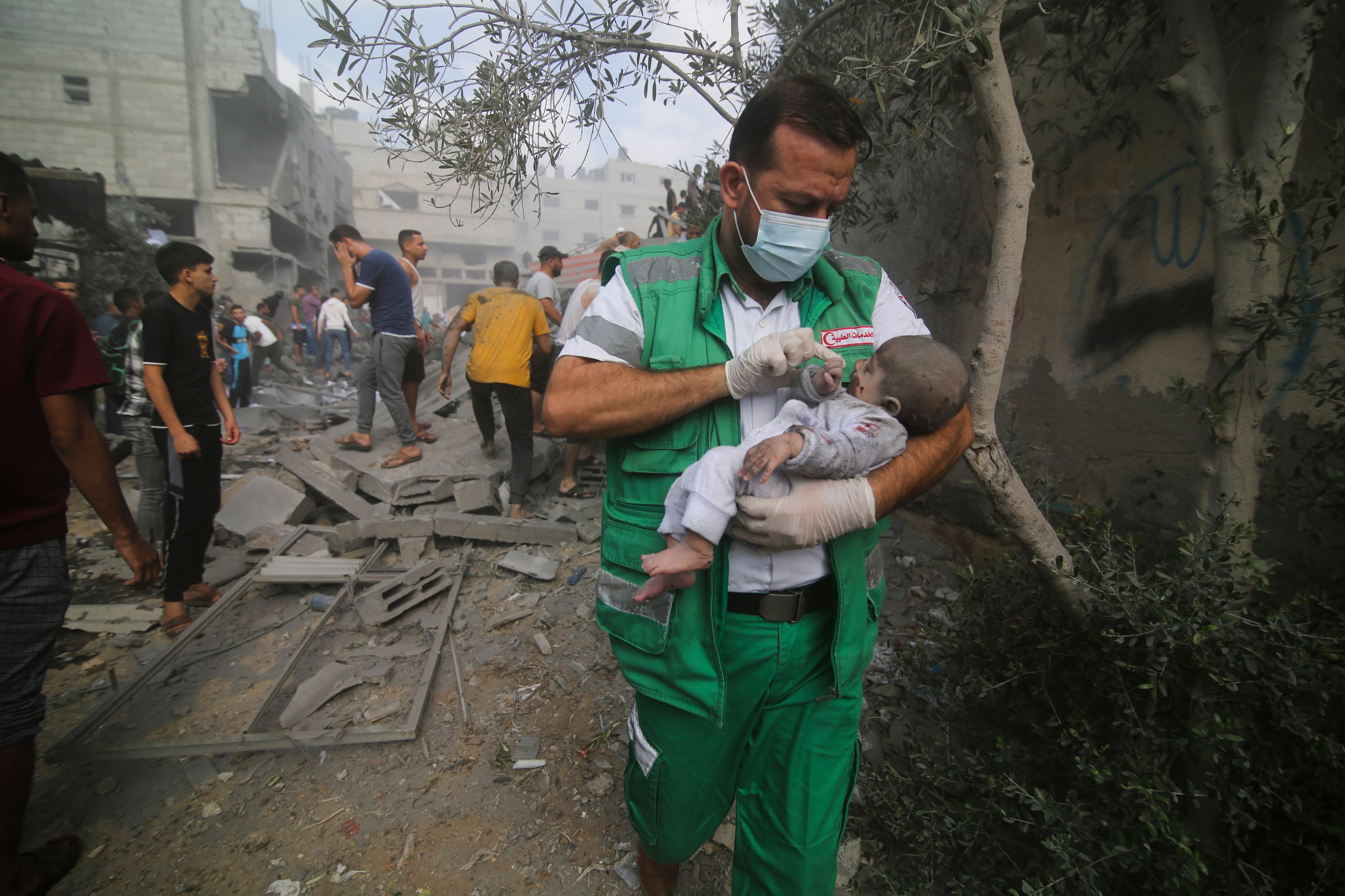 A Palestinian medic carries a baby pulled out of destroyed buildings.