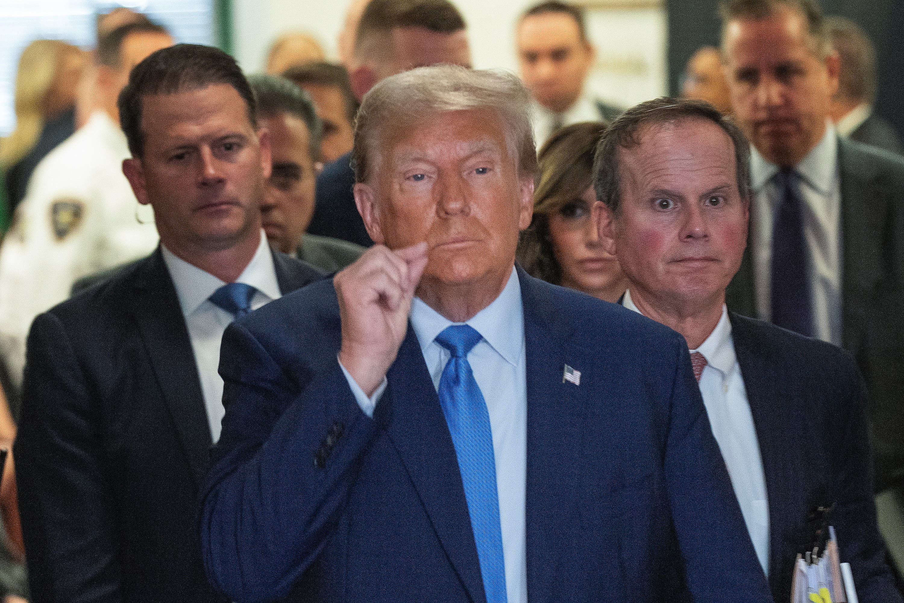 Former President Donald Trump motions a zipped lip as he walks out of the courtroom.