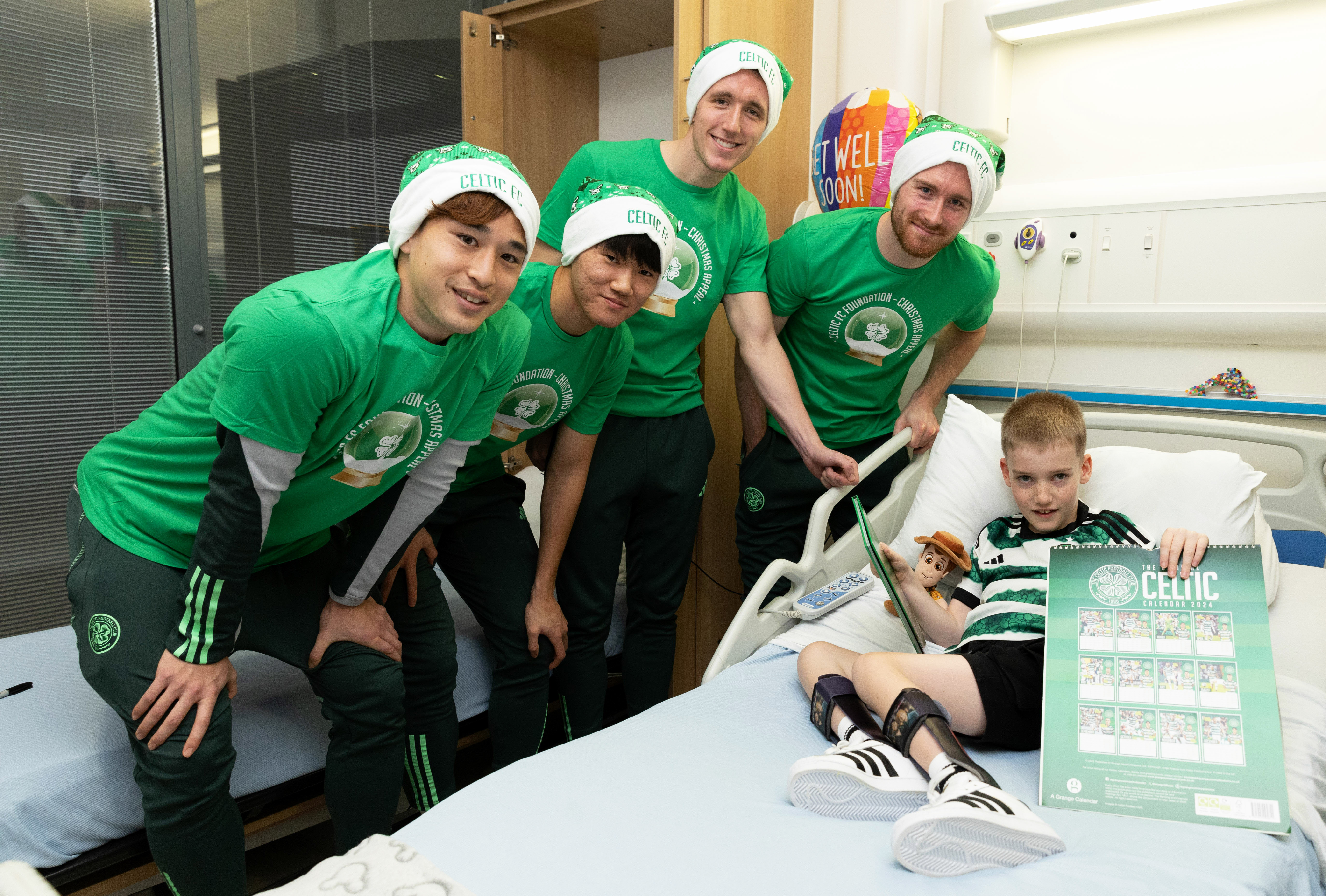 GLASGOW, SCOTLAND - DECEMBER 04: Celtic's Yuki Kobayashi, Yang Hyun-Jun, David Turnbull and Anthony Ralston alongside young fan Jaxon during a Celtic Football Club Christmas visit to the Royal Hospital for Children, on December 04, 2023, in Glasgow, Scotland. (Photo by Craig Williamson / SNS Group)