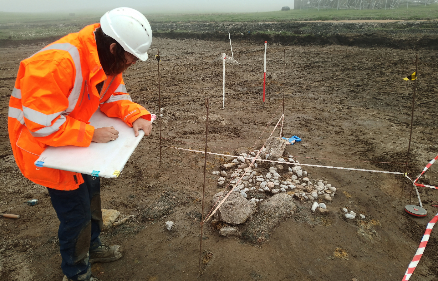 A collection of stones and quartz pebbles in the ground at the large excavation site of a Bronze Age discovery at Shetland Spaceport Site.