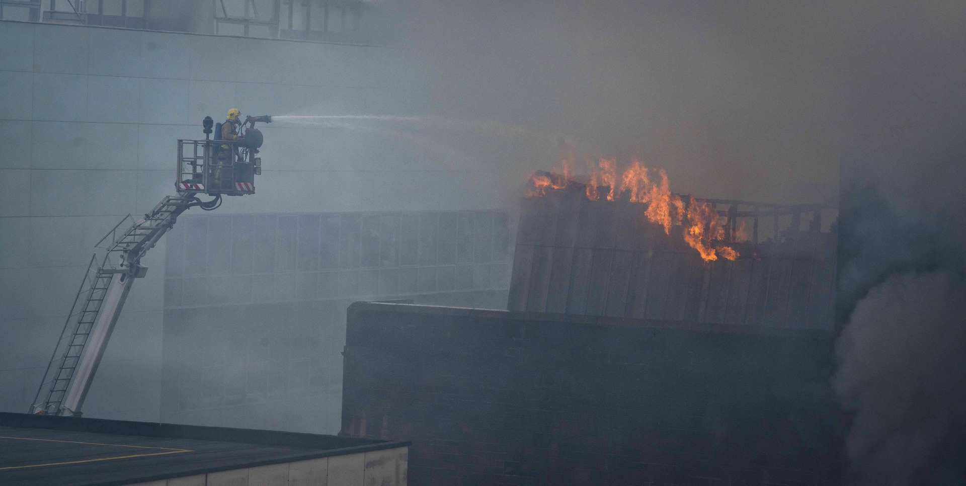 GLASGOW, SCOTLAND - MAY 23:  A firefighter works to put out a fire at the Glasgow School of Art Charles Rennie Mackintosh Building on May 23, 2014 