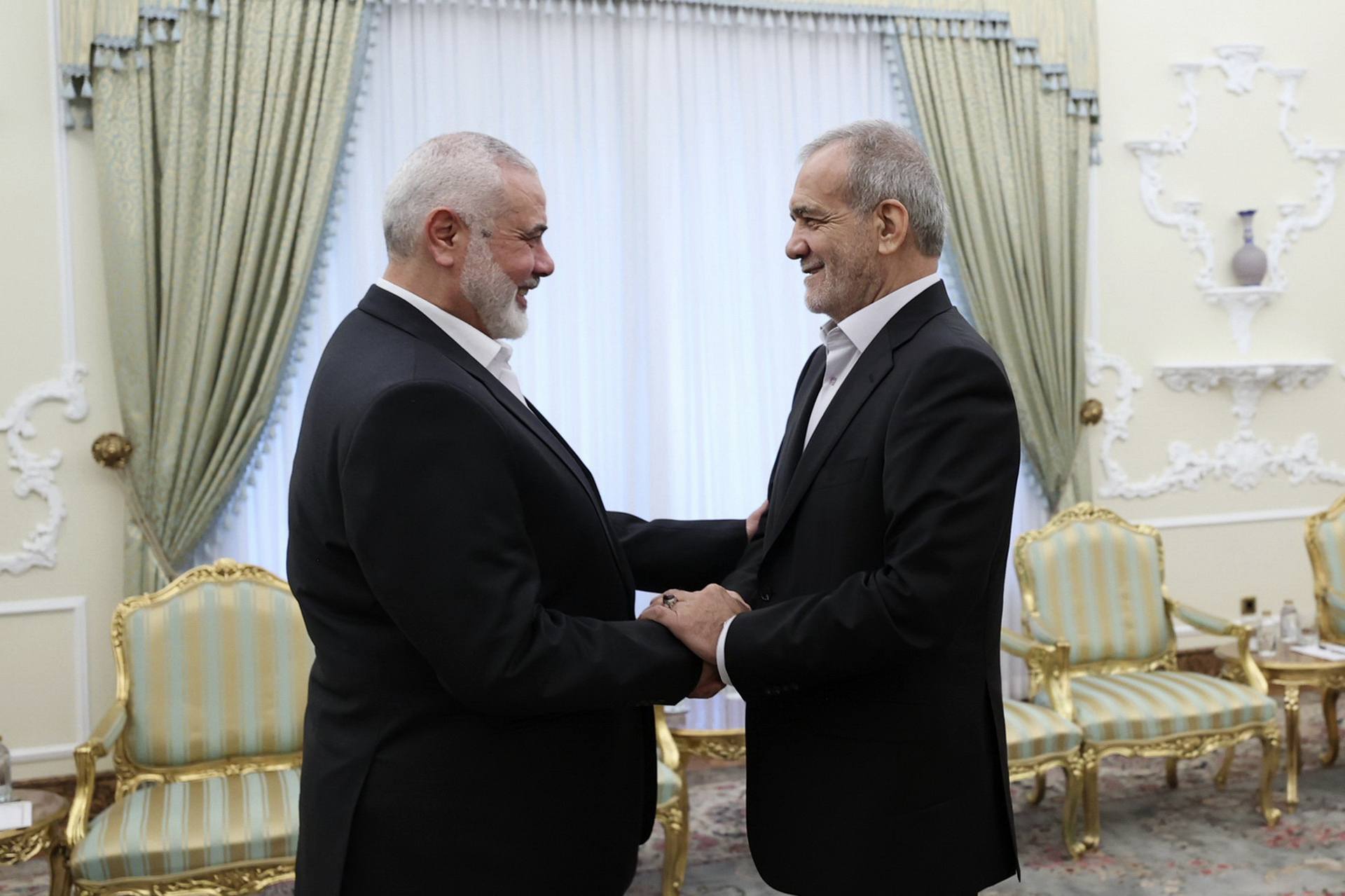 In this photo released by the Iranian Presidency Office, president Masoud Pezeshkian, right, shakes hands with Hamas chief Ismail Haniyeh (Iranian Presidency Office via AP) 