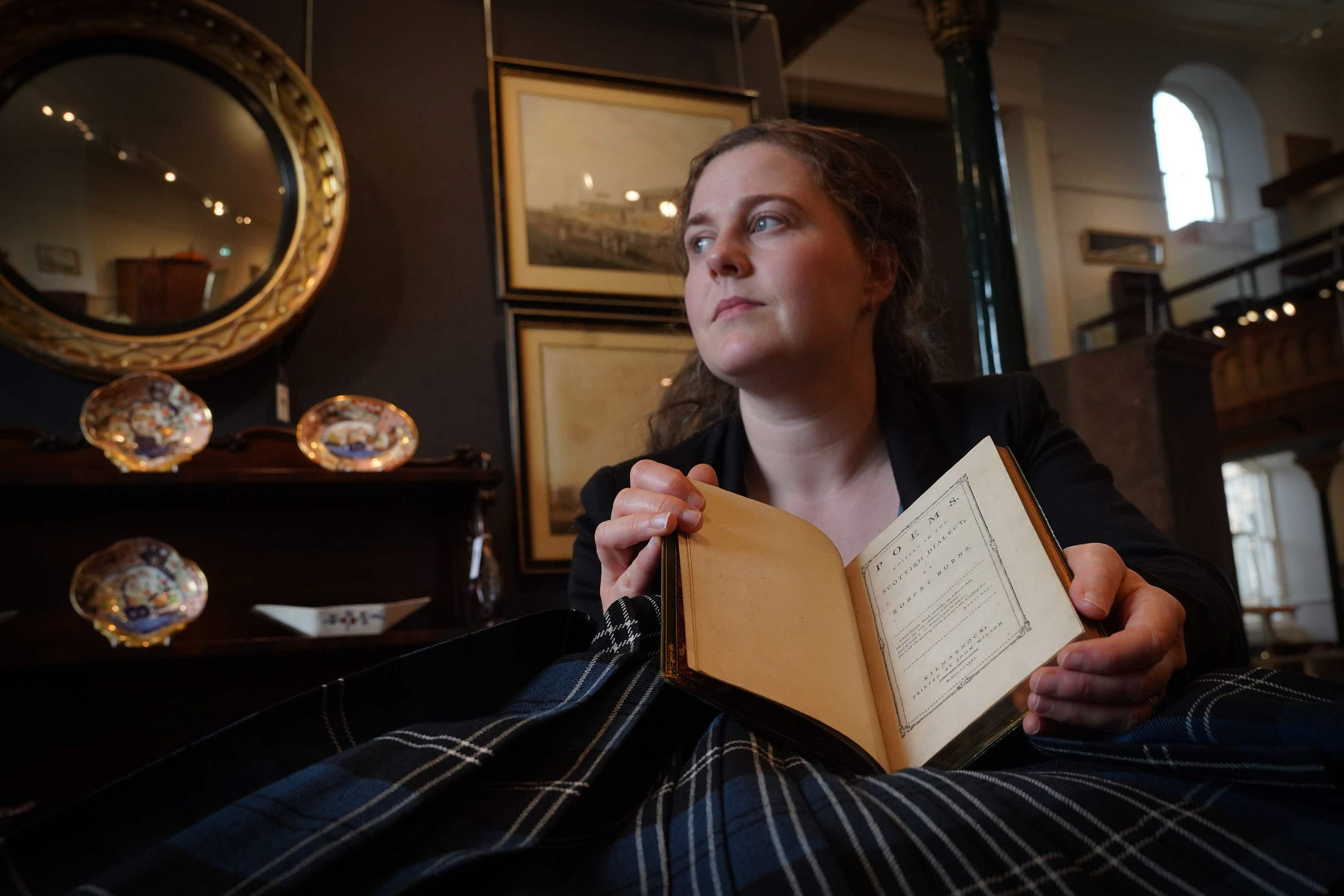 Cathy Marsden of Lyon & Turnbull holds the book (Lyon & Turnbull/Stewart Attwood/PA) 