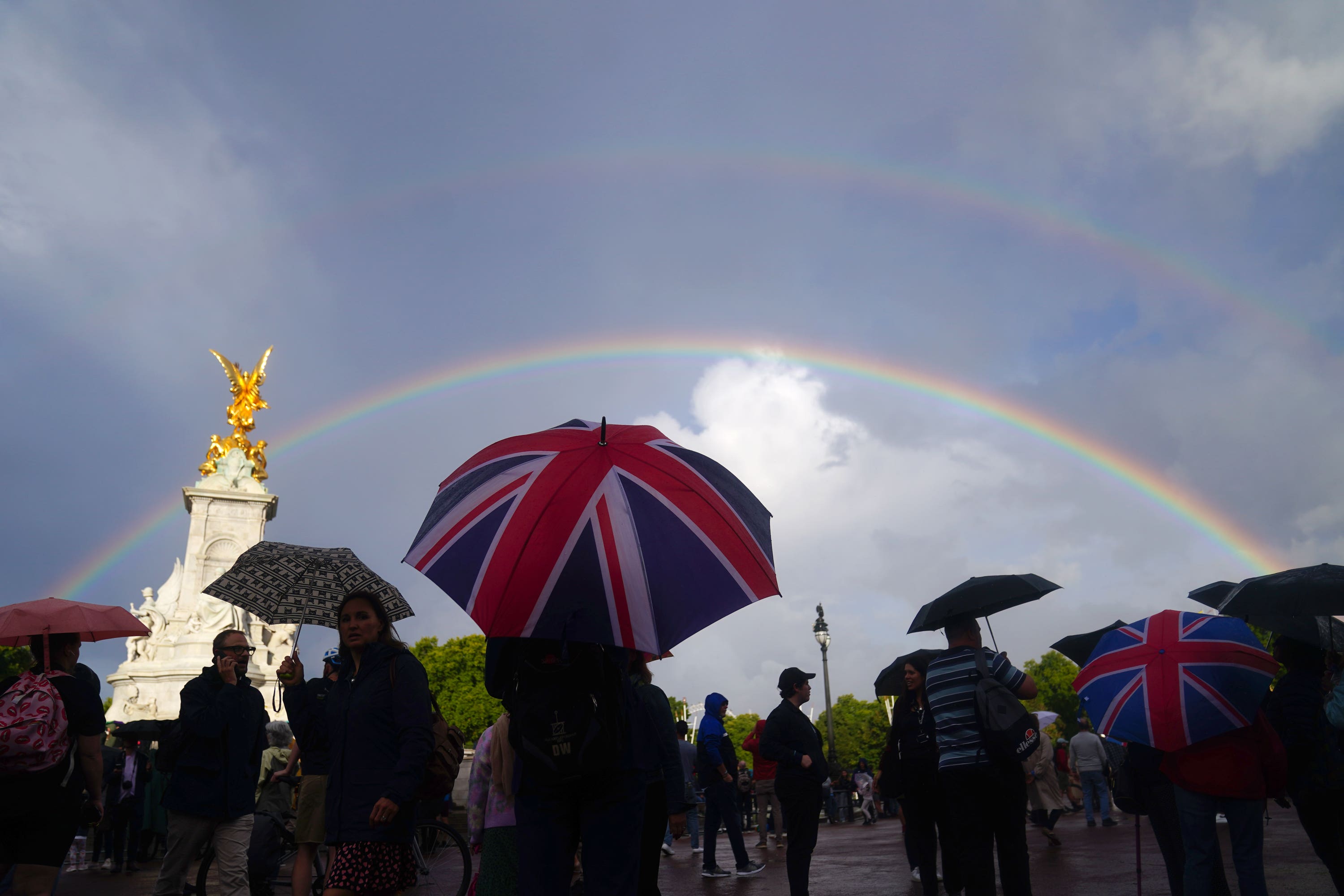 A double rainbow is seen, as members of the public gather outside Buckingham Palace (Victoria Jones/PA). 