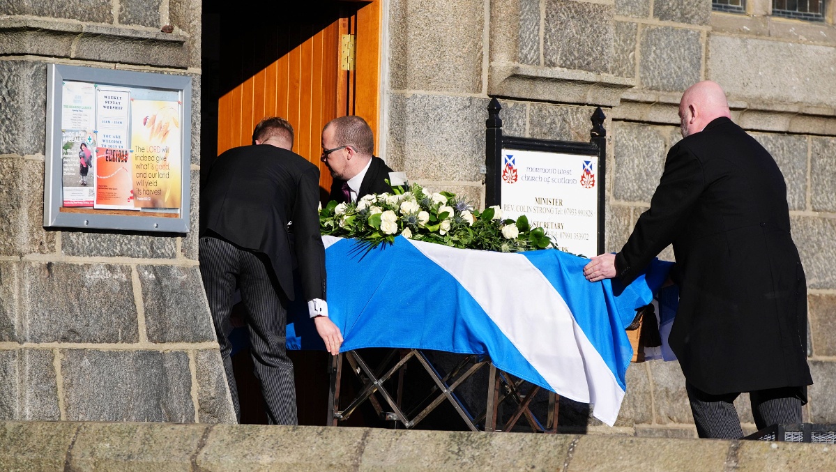 Pall bearers drape a Saltire flag over the coffin as it arrives at the funeral service for former first minister of Scotland Alex Salmond, at Strichen Parish Church