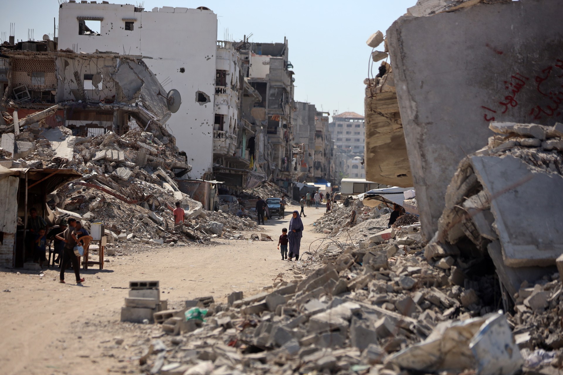 People walking past destroyed buildings in Gaza, October 2024