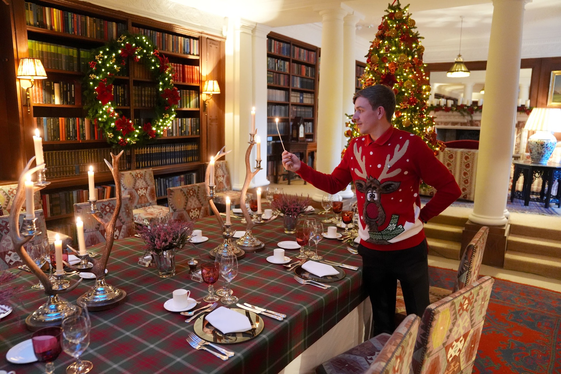 Dumfries House steward Joe Mackie lights candles on a dining table in the library (Dumfries House/PA) 