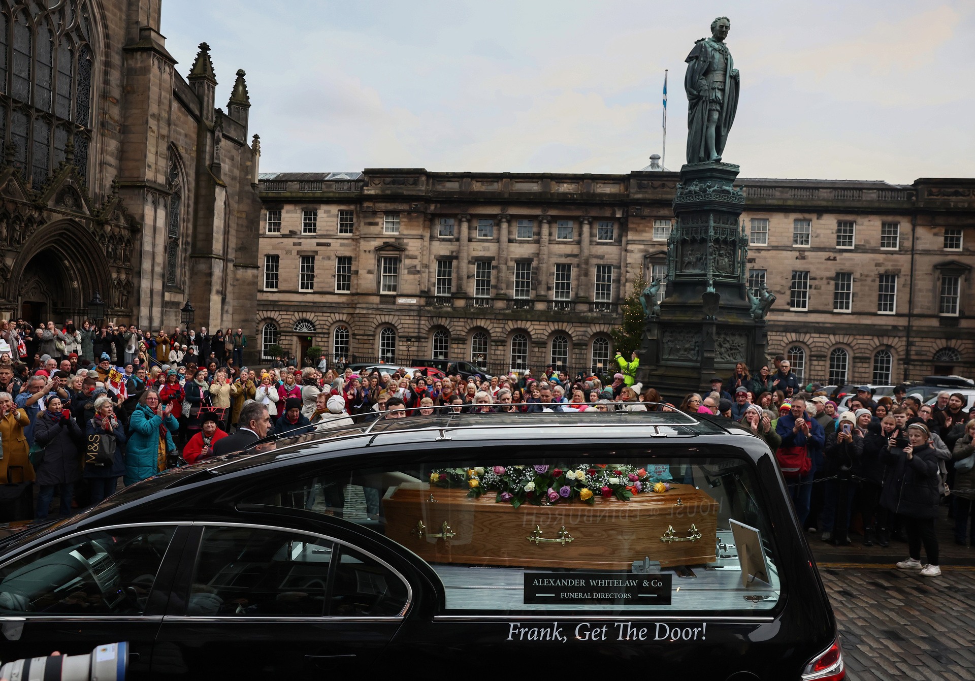 Members of the public look on as the hearse carrying Janey Godley makes its way down The Royal Mile for the comedian's final farewell.