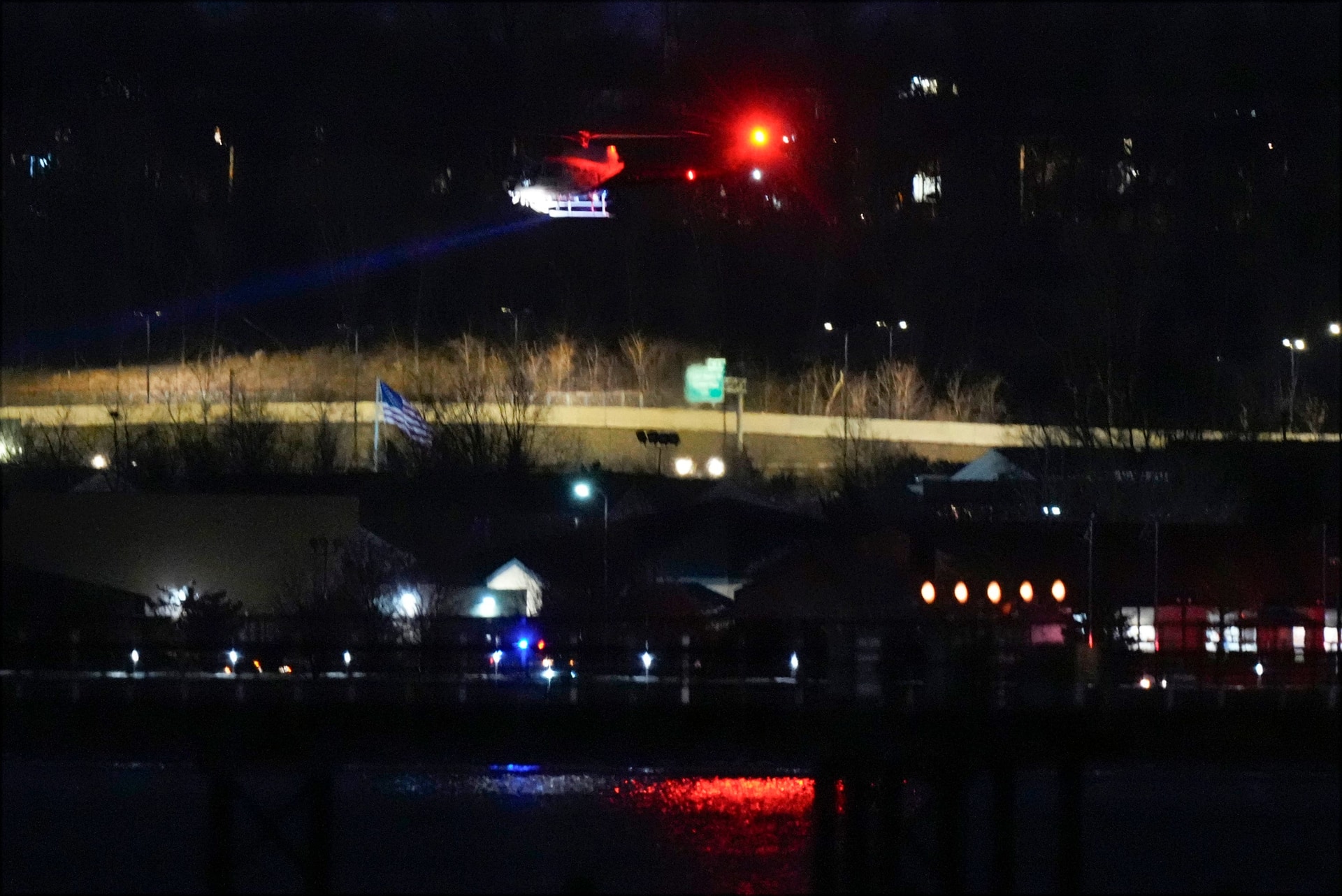 A helicopter uses its searchlight as it flies above the Potomac River near Ronald Reagan Washington National Airport (AP Photo/Alex Brandon) 