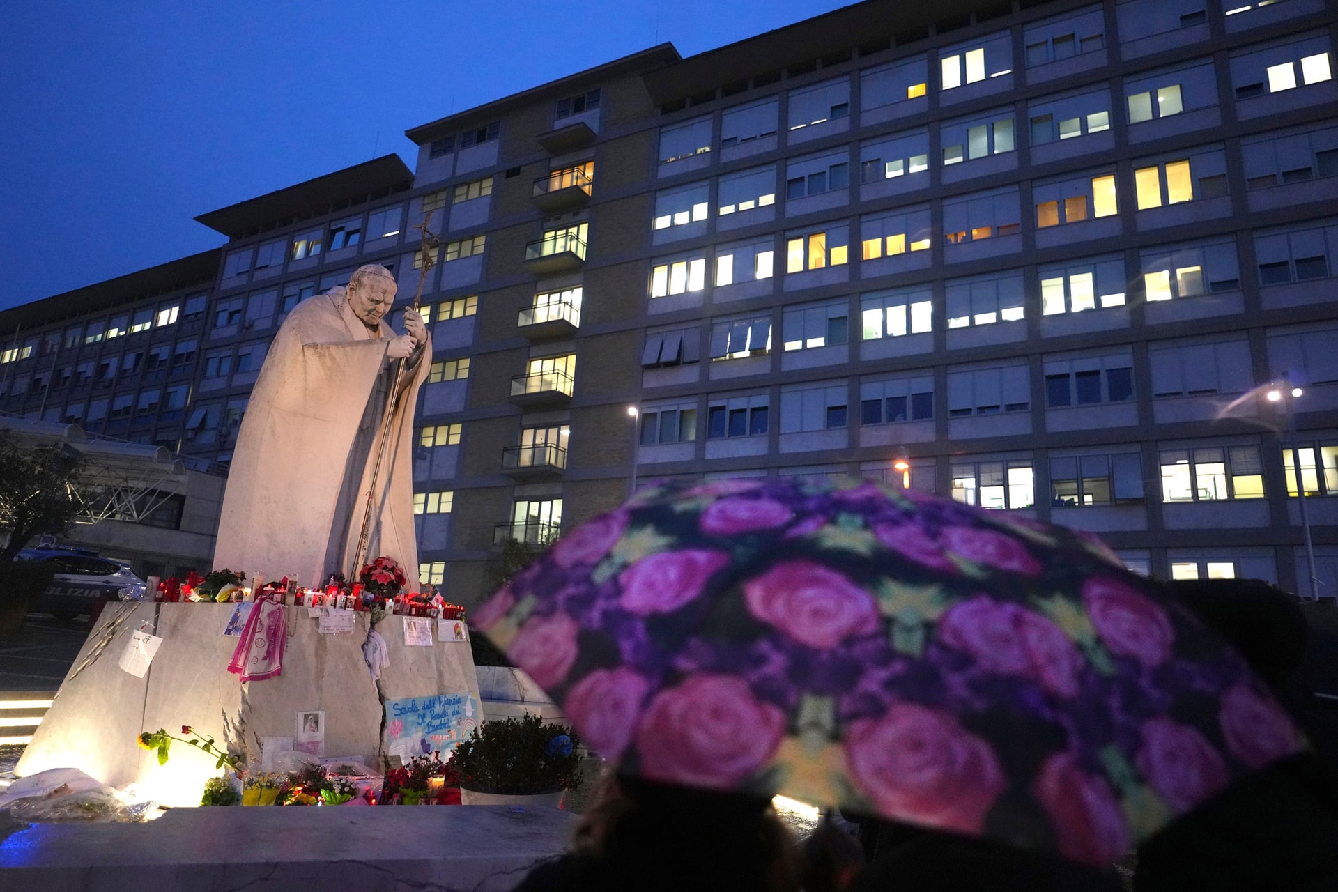 People shelter from the rain as they pray for Pope Francis in front of the Agostino Gemelli Polyclinic in Rome (Kirsty Wigglesworth/AP) 