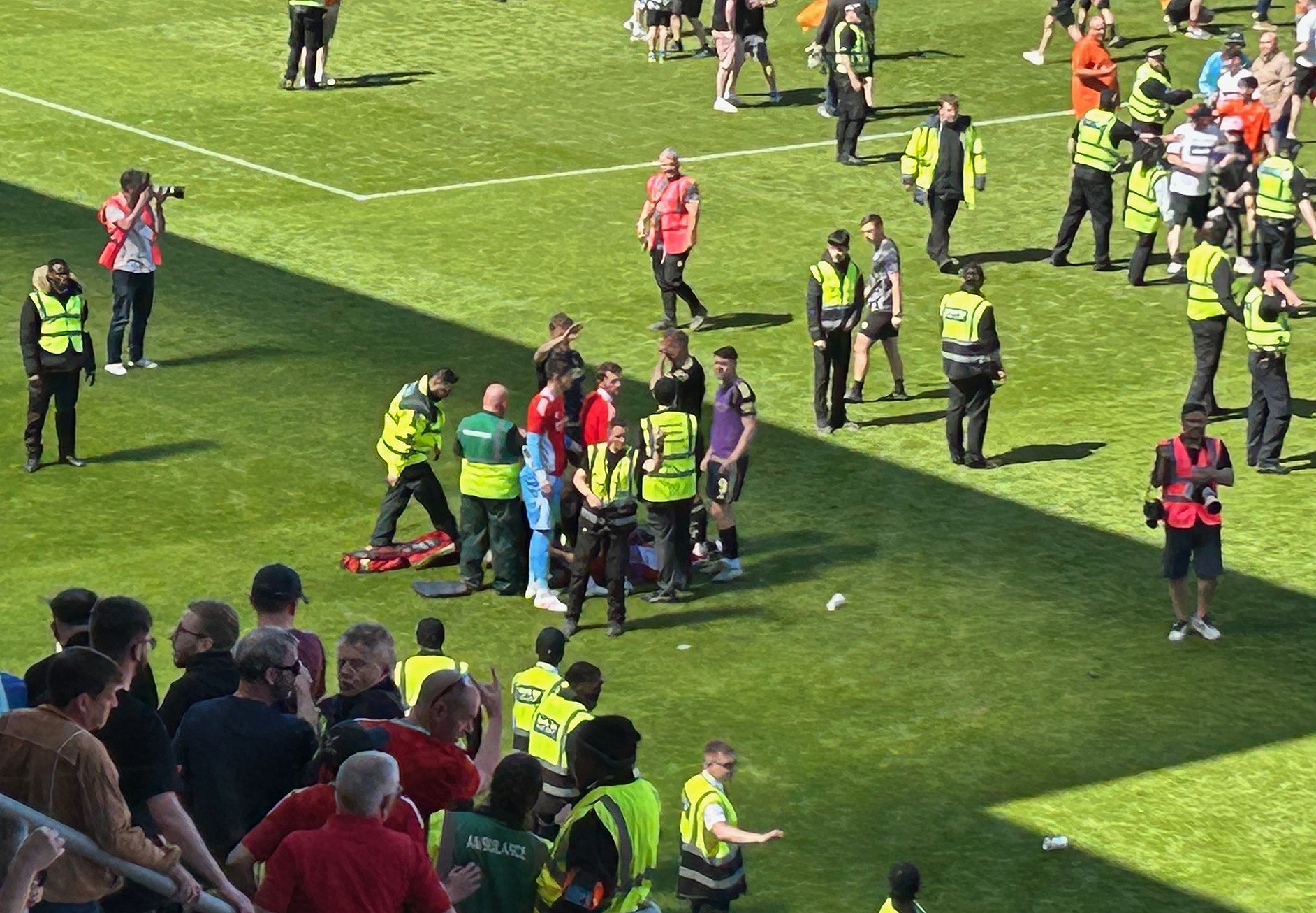 Aberdeen's Jack MacKenzie gets treatment on the pitch as fans invade the pitch after Dundee United's victory over Aberdeen at Tannadice Park, Dundee. Picture date: Saturday May 17, 2025.