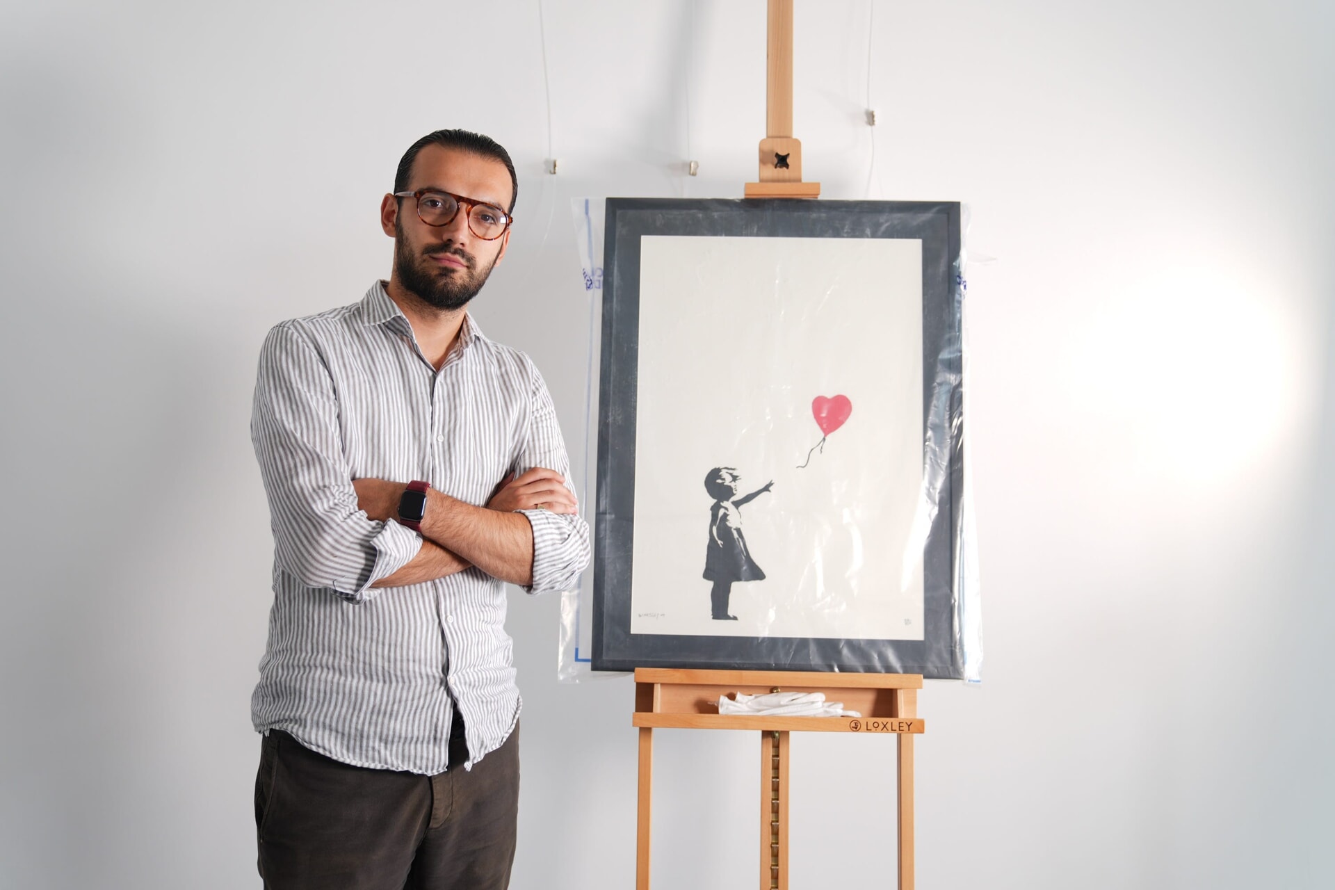 Gallery manager Lindor Mehmetaj stands with a Banksy artwork, Girl With Balloon, at the Grove Gallery in London after it was stolen then recovered.
