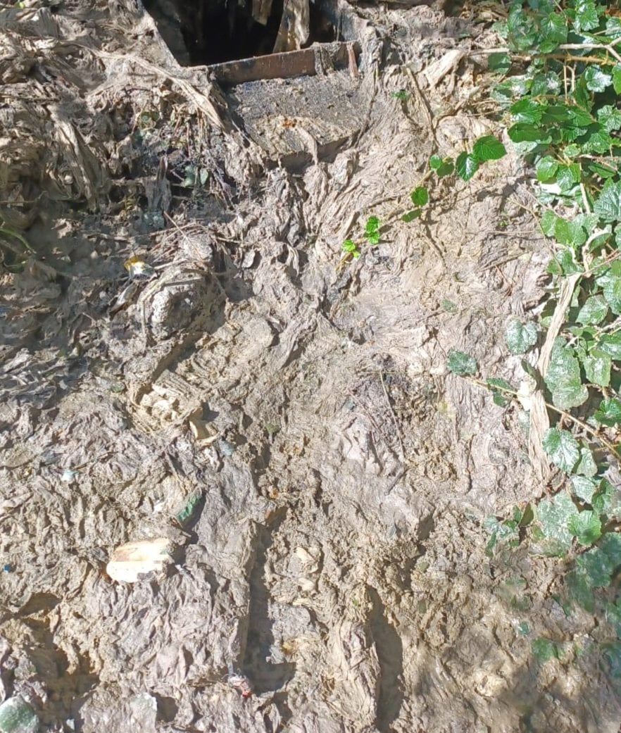 A blocked sewer surrounded by wet wipes and sewer-related debris.