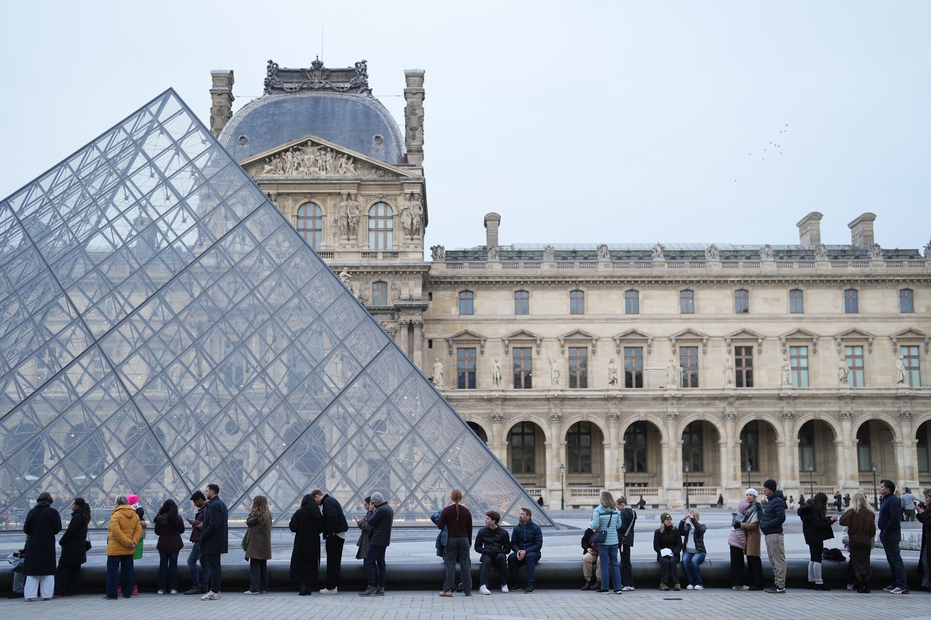 People wait for the Louvre museum to open.