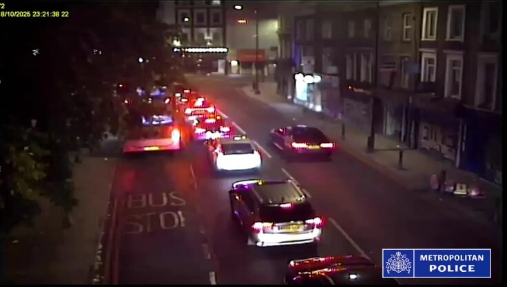 CCTV of the BMW (right) being driven on the wrong side of the road past cars stopped at traffic lights in London