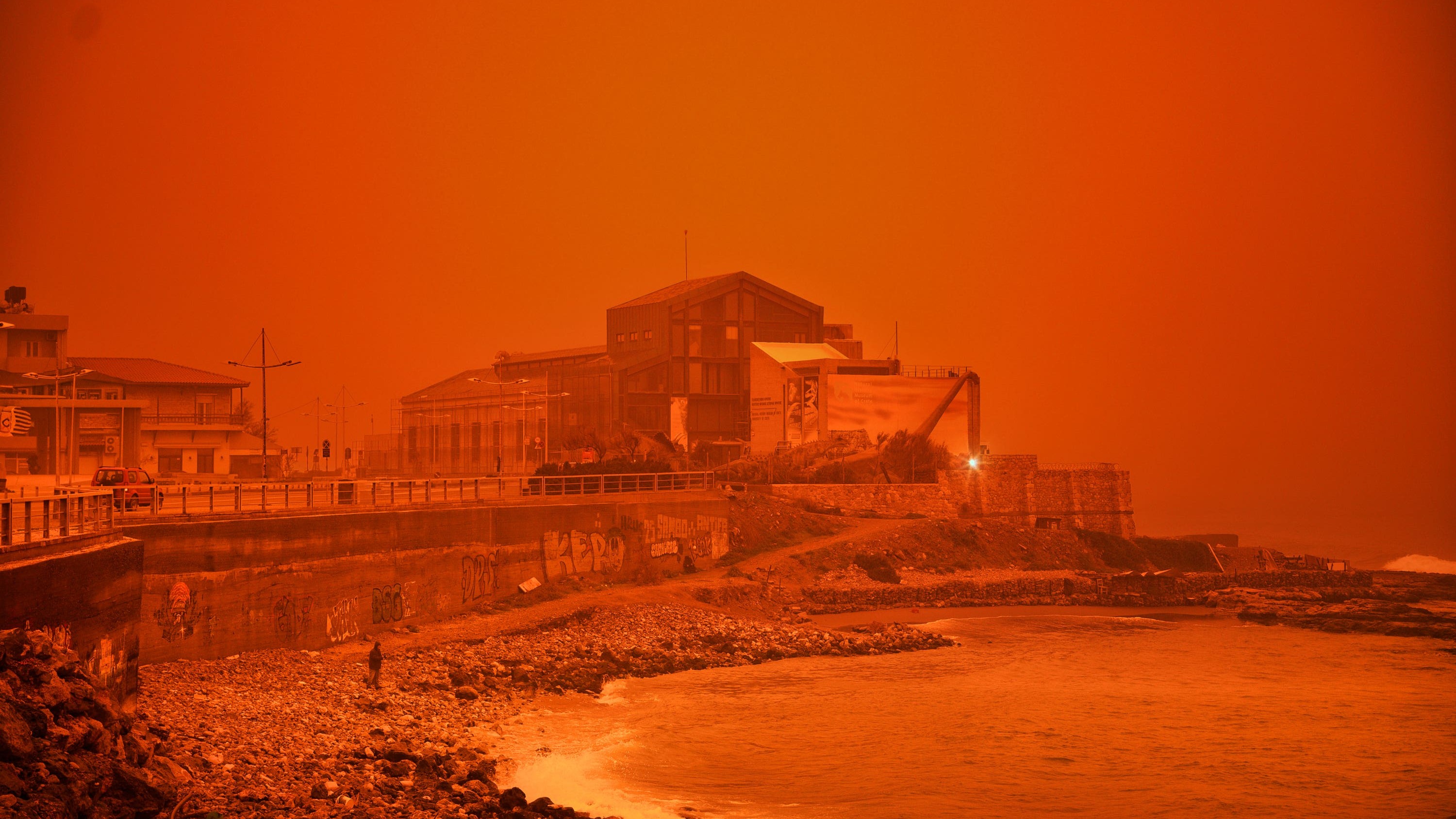 A man walks at a beach during a dust storm on the island of Crete