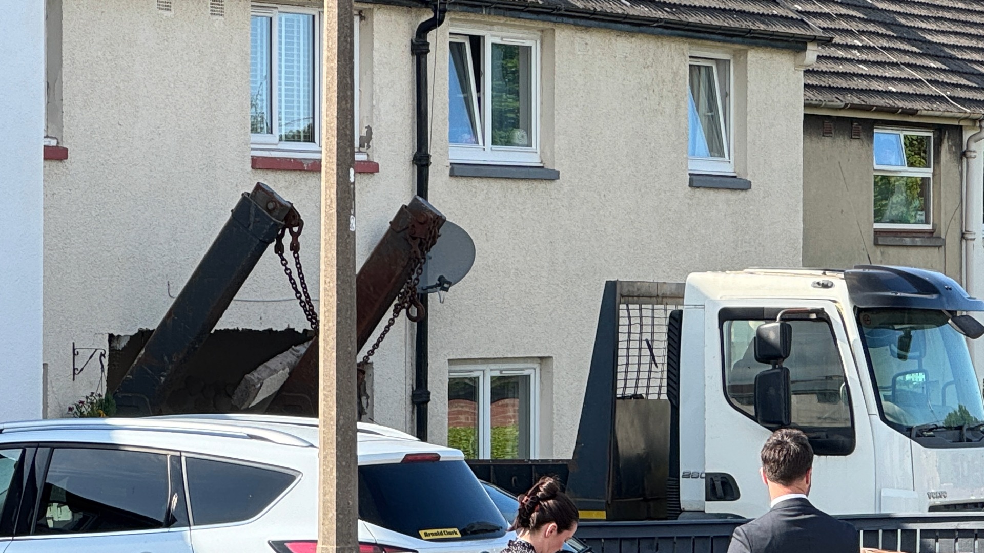 The skip lorry reversed into the building at speed.