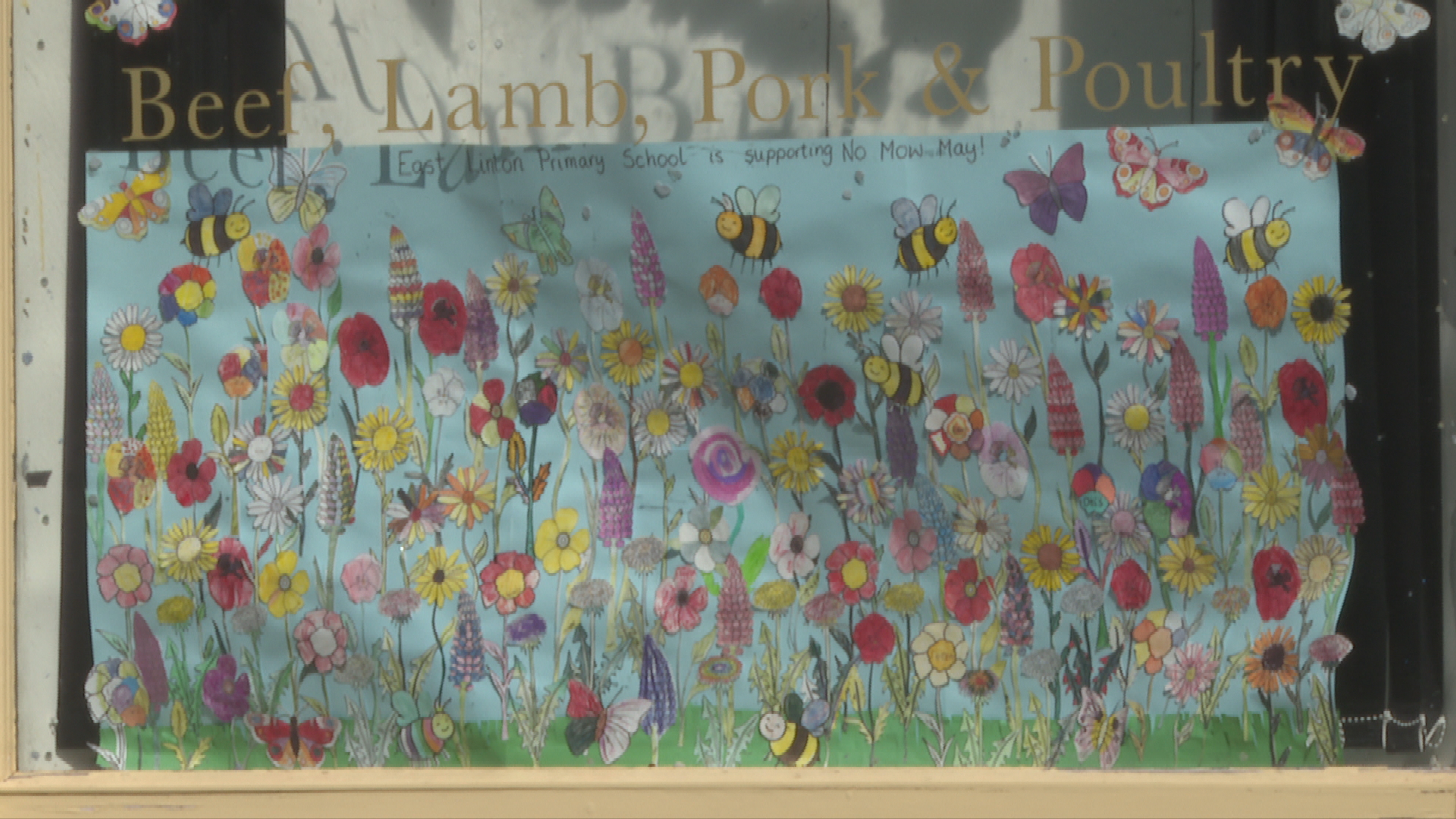 School children create flower banner for the local butcher shop